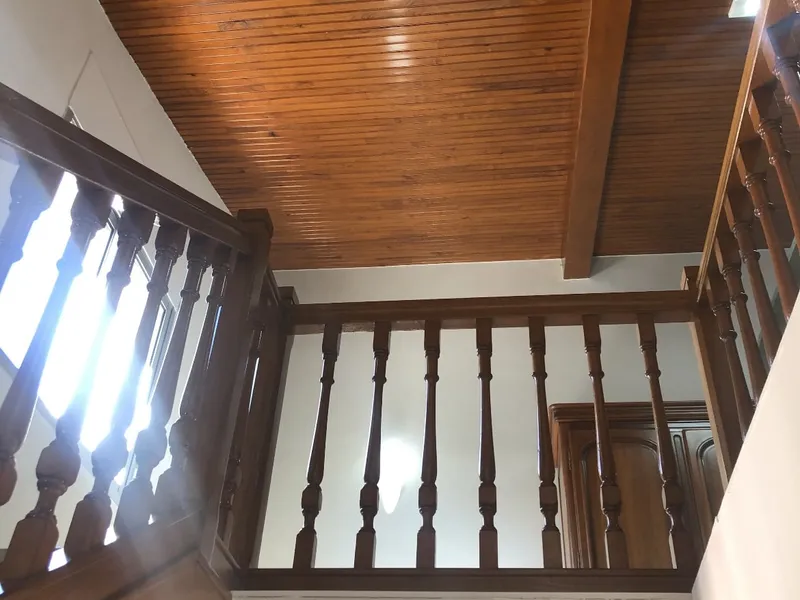 Plafond en lambris et garde-corps à balustres en bois teinté, vus d’en bas