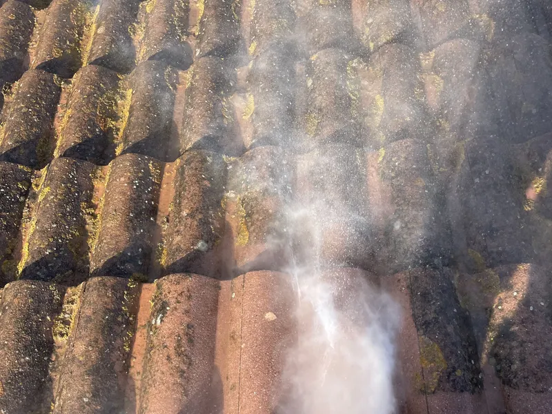Jet d’eau sur des tuiles canal couvertes de mousse pendant le démoussage